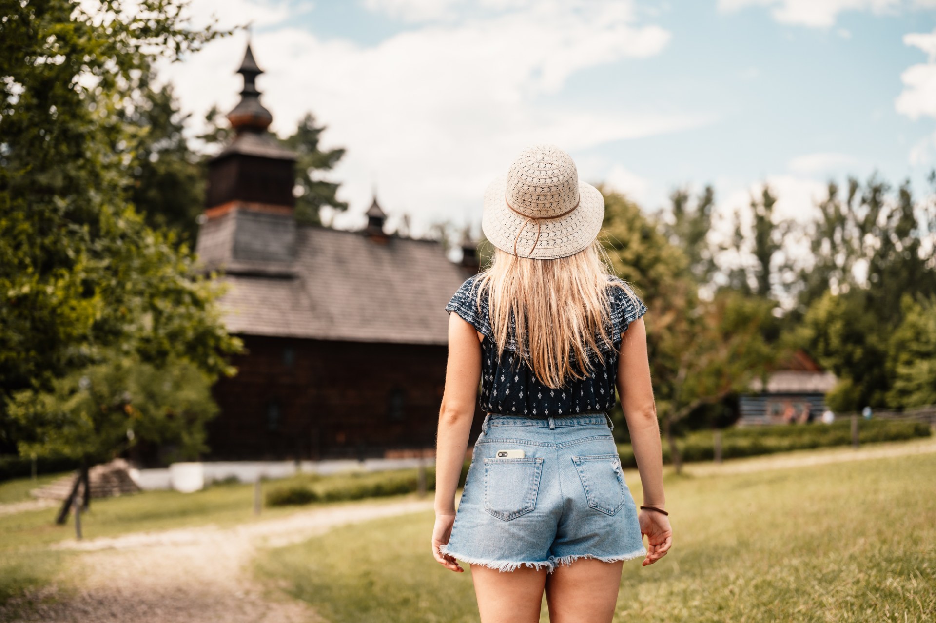 Joven caminando por el museo al aire libre de Stará Ľubovňa hacia una iglesia de madera